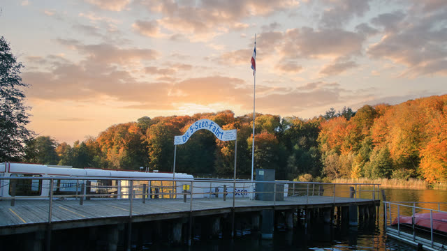 Anleger der 5-Seen-Fahrt am Dieksee in Malente im Abendlicht, dahinter herbstlich gefärbter Wald